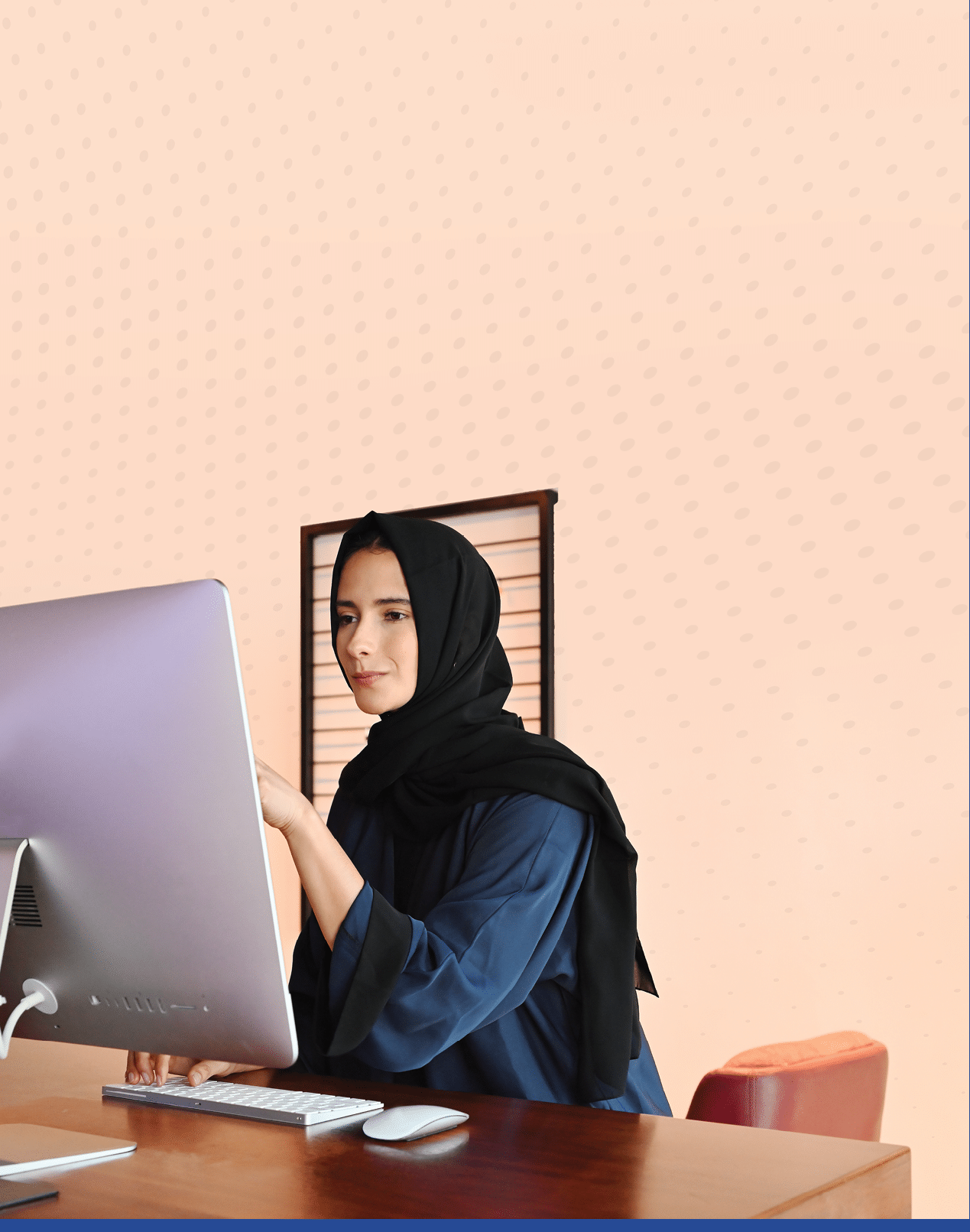 Beautiful Middle Eastern woman using desktop computer screen wearing traditional Hijab and Abaya head scarf.