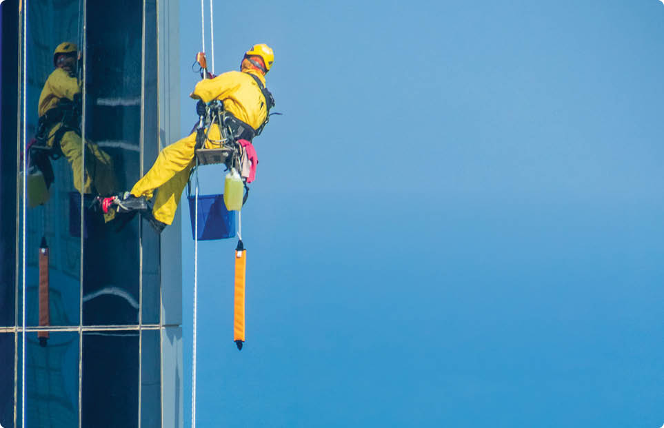 Worker Cleaning a Facade of One of the Buildings in Downtown Abu Dhabi. Abu Dhabi - UAE. 19 December 2018