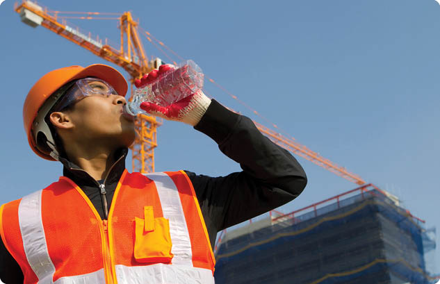 worker man as he drinks from a plastic water bottle on construction site