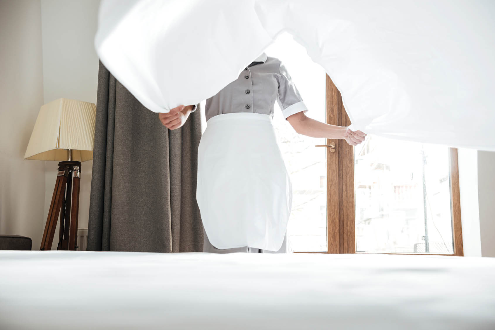 Cropped image of a hotel maid changing the bed sheets