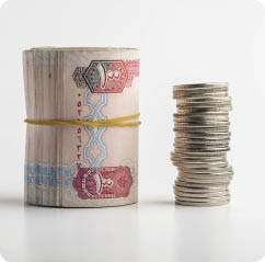 Rolled Hundred dirham bills placed along with stack of coins on white background. Return on investment- a concept.